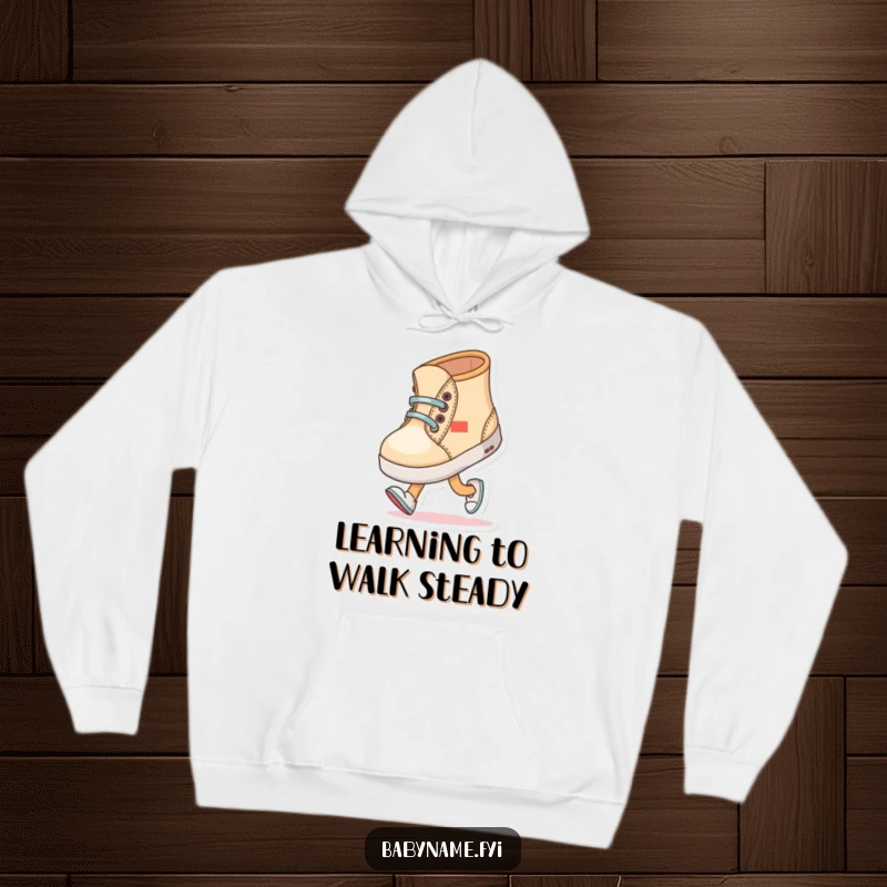 Funny baby shoe character comically trying to walk with wobbly steps, featured on a warm and humorous hoodie.