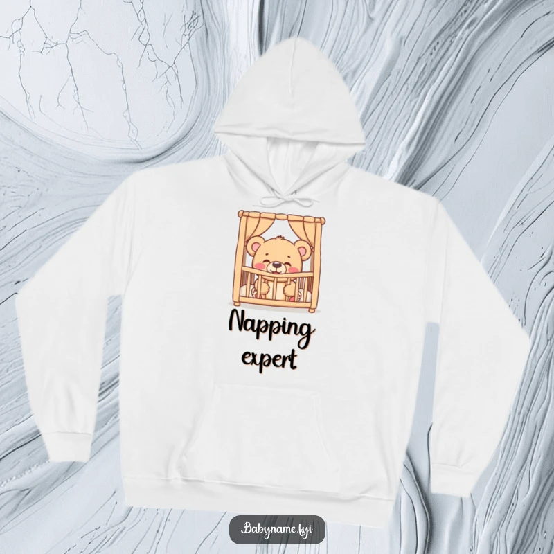 Funny giggling teddy bear peeking from a crib, printed on a warm hoodie, capturing sweet and humorous baby-themed joy.